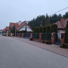 Ulica w Białowieży z domami z czerwonymi dachami i żywopłotami. Może to dom Zenka Martyniuka w Białowieży?