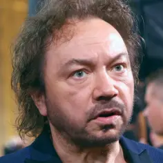 Zbliżenie na twarz mężczyzny z kręconymi włosami i niebieskimi oczami. Czyżby to był Mietek Szcześniak, nasz partner w muzycznej podróży?