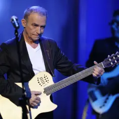 Seweryn Krajewski dzisiaj na scenie, grając na gitarze. W tle basista.