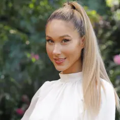 Ida Nowakowska zwolniona z TVP, uśmiechnięta blondynka w białej bluzce na tle zieleni.