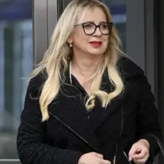 Marzena Rogalska z córką, w czarnym płaszczu i okularach, wychodzi z budynku.
