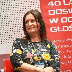 Maria Gutowska, córka Niemena, w kwiecistej sukience, z uśmiechem na twarzy, na tle napisu "40 lat doświadczenia w doskonałym brzmieniu".