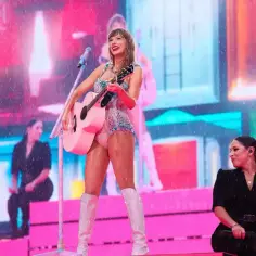Taylor Swift, ile lat ma, na scenie z różową gitarą, w błyszczącym stroju i białych kozakach.