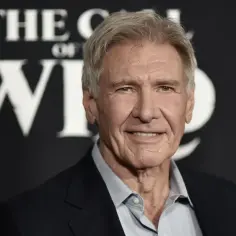 Harrison Ford, który ma 81 lat, uśmiecha się na tle napisu "The Call of the Wild".