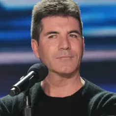 Simon Cowell przed mikrofonem, wygląda na zamyślonego. Plotki o tym, czy Simon Cowell nie żyje, są nieprawdziwe.