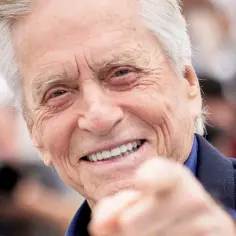 Uśmiechnięty Michael Douglas, który ma 79 lat, wskazuje palcem w obiektyw.