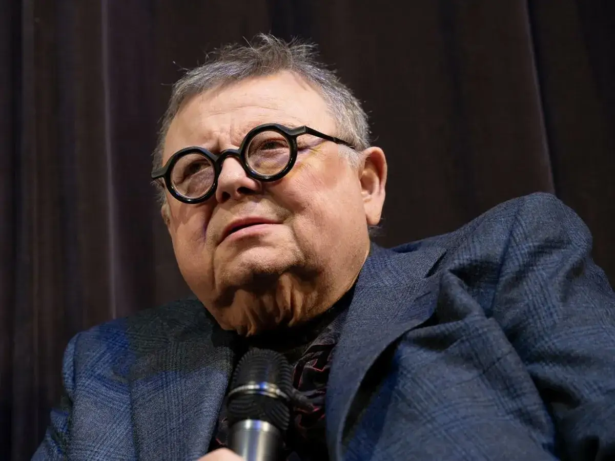 Wojciech Mann w okularach, w garniturze, z mikrofonem. Ile lat ma Wojciech Mann?
