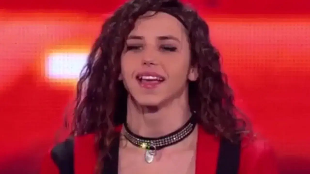 Michał Szpak z żoną na scenie, w czerwonej marynarce i błyszczącym naszyjniku.