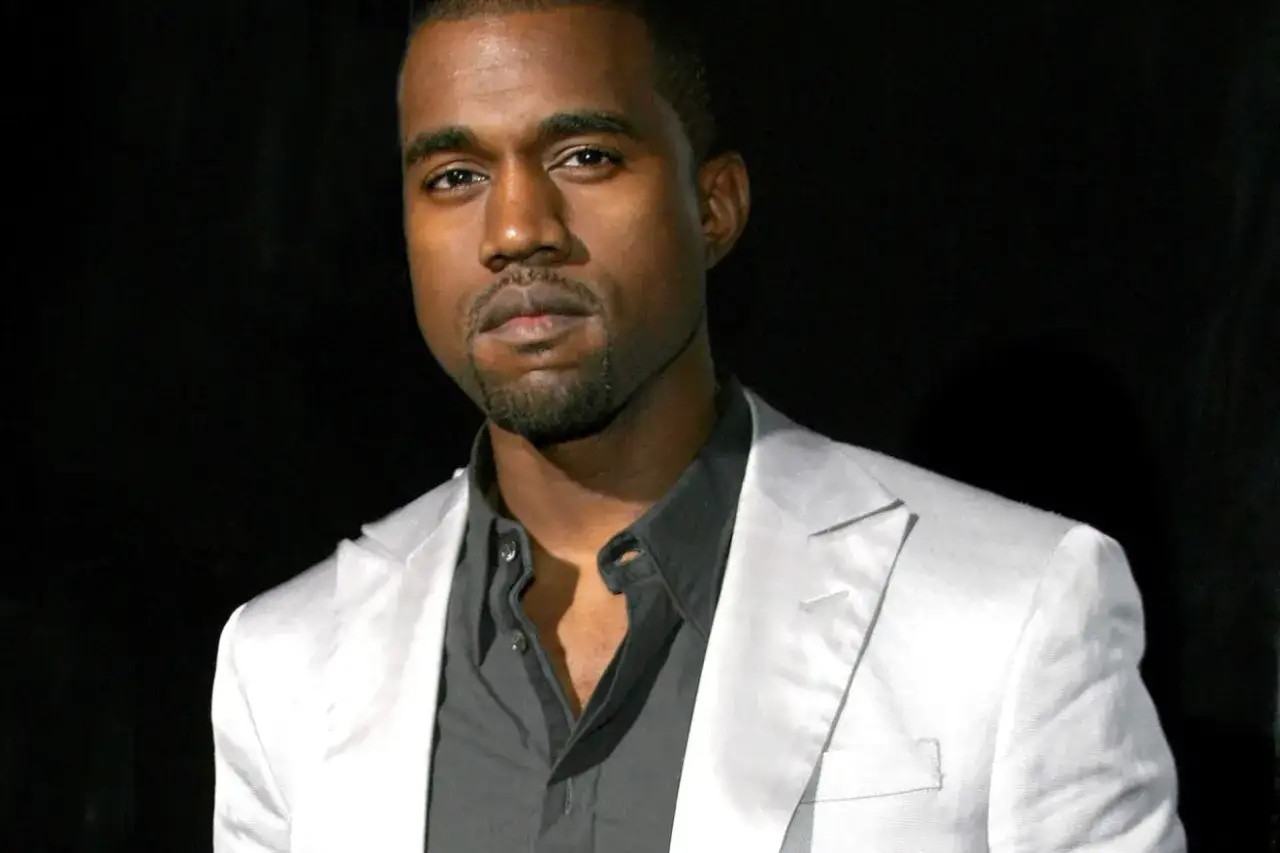 Kanye West w białej marynarce i czarnej koszuli, wygląda na zamyślonego. Czyżby Kanye West chory?