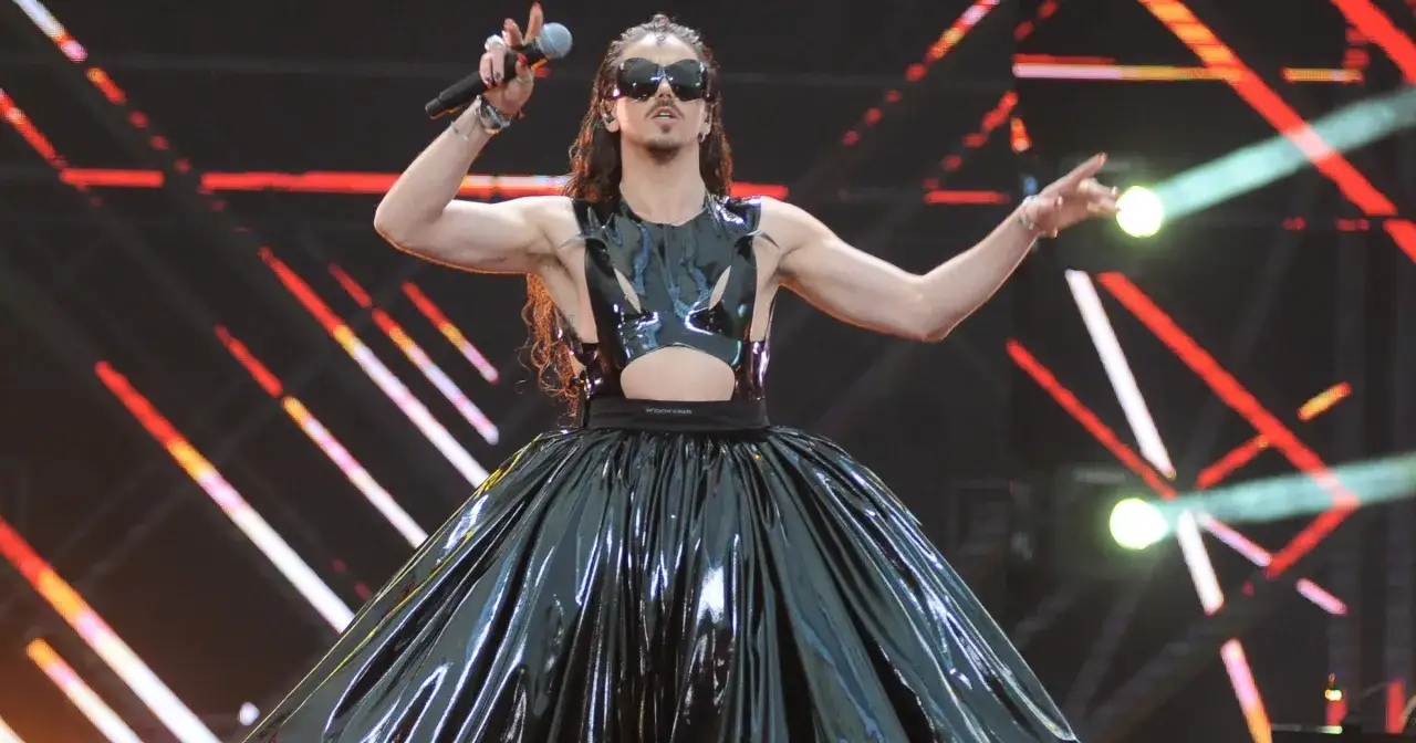 Michał Szpak w błyszczącej, czarnej kreacji z bufiastą spódnicą, śpiewa na scenie. Wygląda jakby szukał swojej żony wśród publiczności.