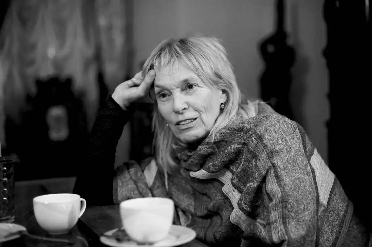 Małgorzata Braunek, zamyślona, z ręką na skroni, przy filiżance kawy. Jej choroba nie definiuje jej siły.